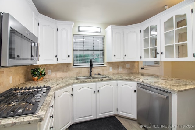 kitchen with tasteful backsplash, white cabinetry, light stone countertops, sink, and stainless steel appliances