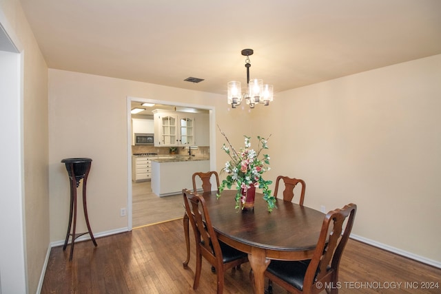 dining area featuring wood-type flooring and an inviting chandelier