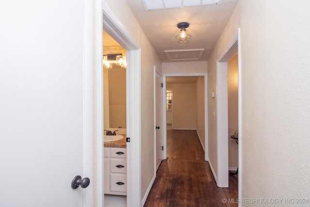 hall with baseboards, a sink, visible vents, and dark wood finished floors