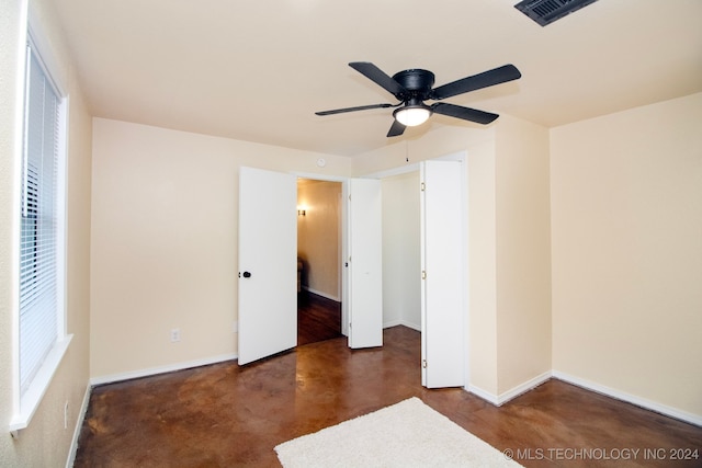 unfurnished bedroom featuring a ceiling fan, baseboards, visible vents, and concrete floors