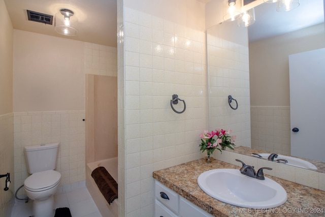 bathroom featuring toilet, vanity, a shower, and tile walls