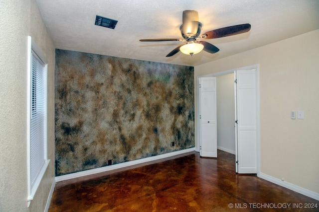 empty room with ceiling fan, baseboards, and finished concrete floors