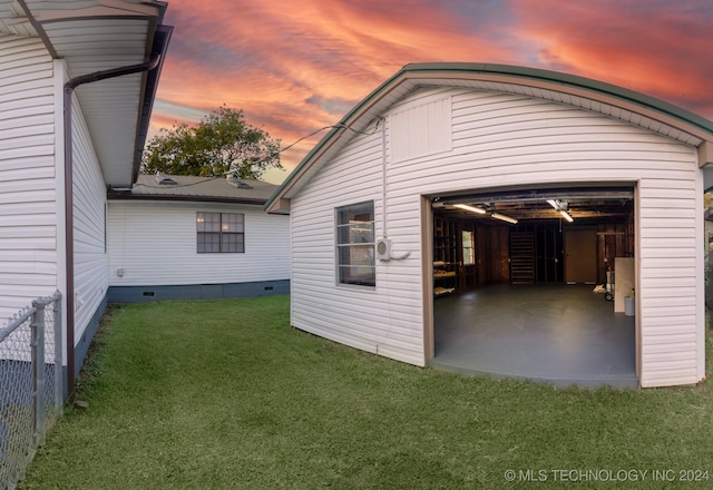 garage at dusk featuring a lawn