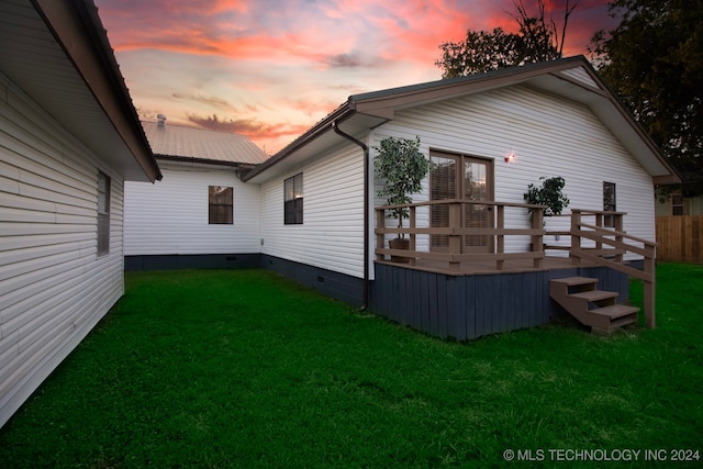 back house at dusk with a yard and a wooden deck