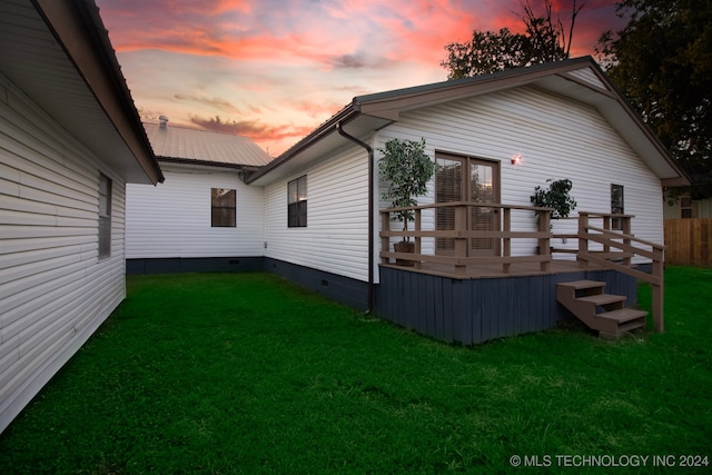 back of property at dusk featuring crawl space, metal roof, a wooden deck, fence, and a yard
