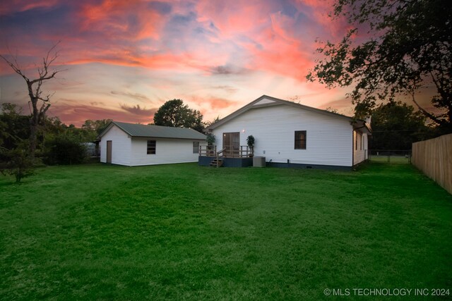 rear view of house featuring a fenced backyard, an outbuilding, a yard, and a deck