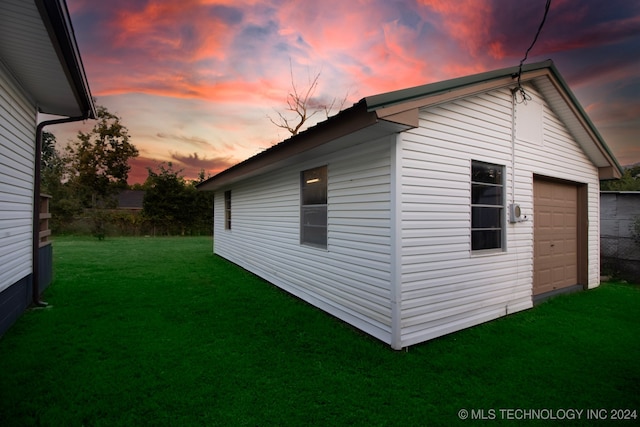 property exterior at dusk featuring a lawn and a garage