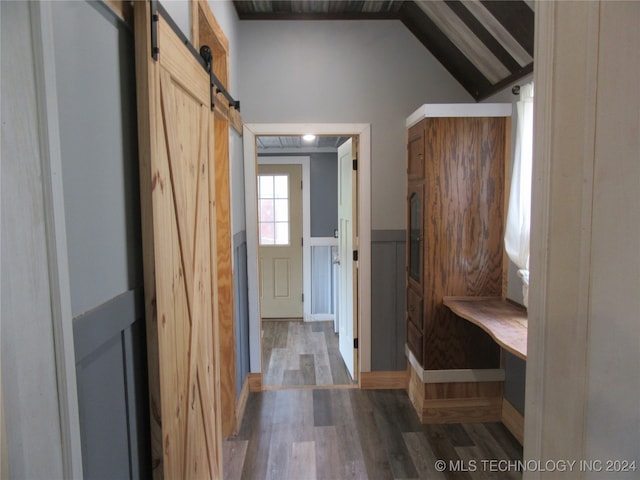 mudroom with vaulted ceiling, a barn door, and hardwood / wood-style flooring