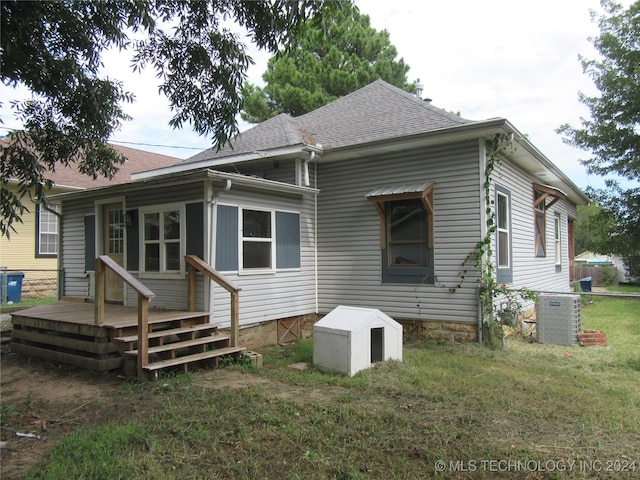 rear view of house with a wooden deck, a yard, and central air condition unit