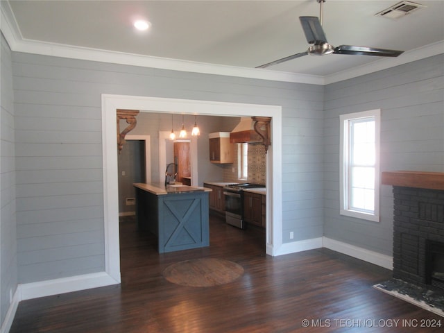 kitchen with an island with sink, pendant lighting, dark hardwood / wood-style flooring, ceiling fan, and stainless steel stove