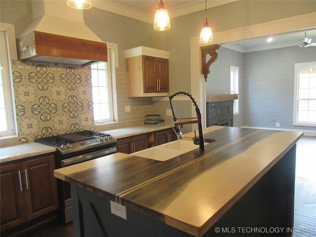 kitchen with sink, gas stove, custom range hood, and crown molding