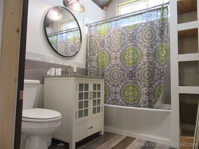 bathroom with vaulted ceiling, tile walls, wood-type flooring, shower / bath combination with curtain, and toilet