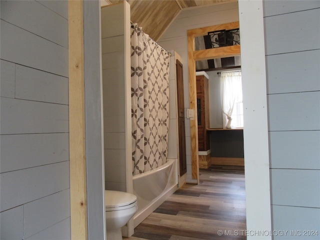 bathroom featuring shower / bathtub combination with curtain, toilet, wood-type flooring, and lofted ceiling