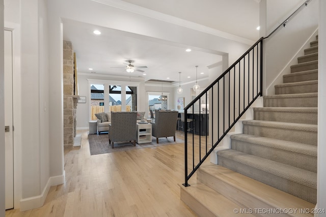 stairs featuring ceiling fan, crown molding, and hardwood / wood-style floors