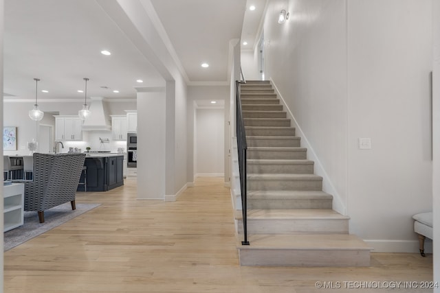 staircase featuring crown molding and wood-type flooring