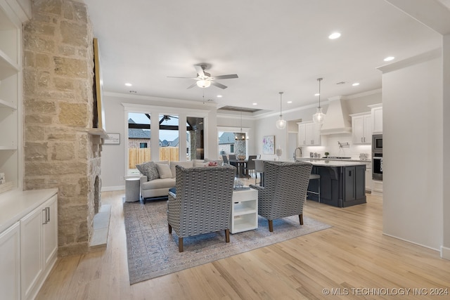 living room featuring light hardwood / wood-style floors, sink, crown molding, and ceiling fan