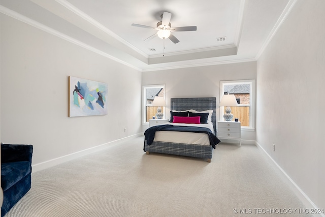 carpeted bedroom with ceiling fan, a raised ceiling, and ornamental molding