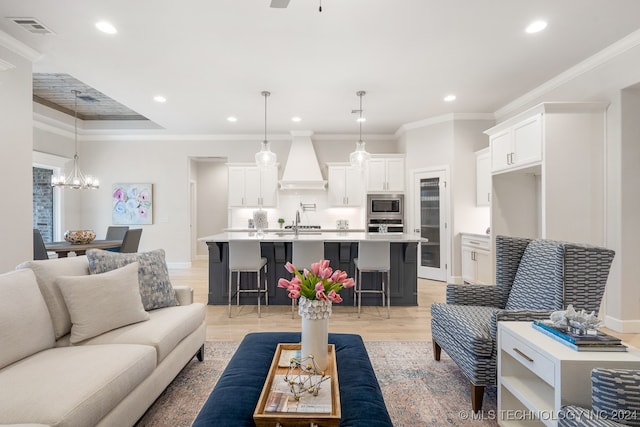 living room featuring sink, light hardwood / wood-style flooring, crown molding, and a chandelier