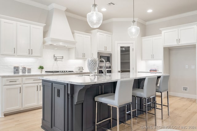 kitchen with custom exhaust hood, tasteful backsplash, light wood-type flooring, and stainless steel appliances