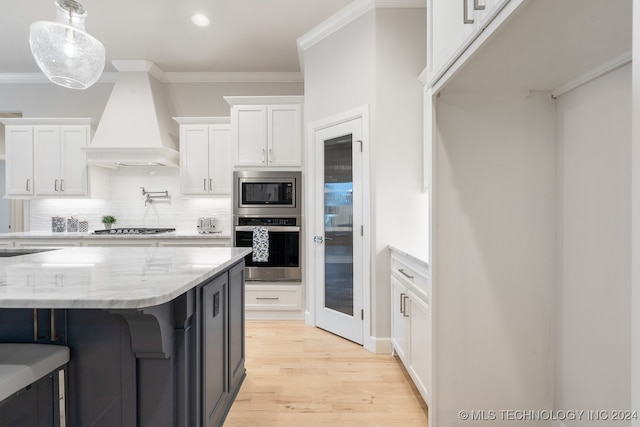 kitchen featuring backsplash, premium range hood, appliances with stainless steel finishes, light stone counters, and light hardwood / wood-style floors