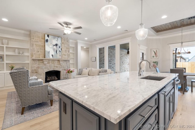 5424 E 125th Pl S, Bixby, OK 74008 - kitchen featuring a sink, crown molding, light wood-style floors, a stone fireplace, and a center island with sink