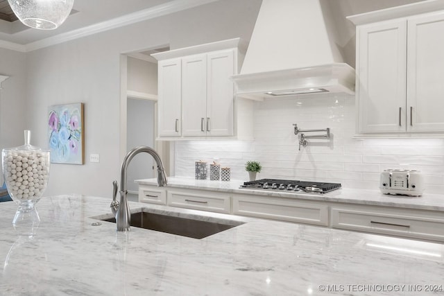 5424 E 125th Pl S, Bixby, OK 74008 - kitchen with custom exhaust hood, a sink, stainless steel gas stovetop, white cabinets, and backsplash