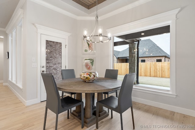 dining area featuring light wood-type flooring, a notable chandelier, and a tray ceiling