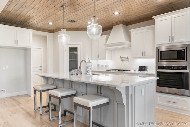 kitchen with light wood-type flooring, appliances with stainless steel finishes, custom exhaust hood, decorative backsplash, and wooden ceiling