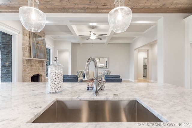 kitchen with sink, a fireplace, beamed ceiling, ceiling fan, and hanging light fixtures