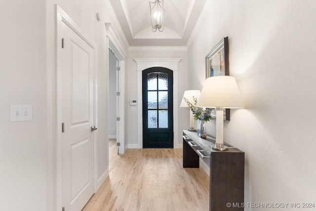 foyer entrance with light hardwood / wood-style floors, a raised ceiling, and ornamental molding