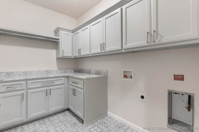 laundry area featuring electric dryer hookup, hookup for a washing machine, cabinets, and light tile patterned flooring