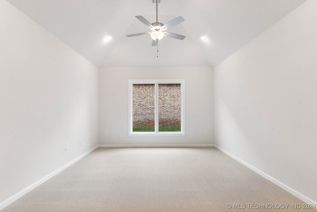 carpeted spare room with ceiling fan and vaulted ceiling