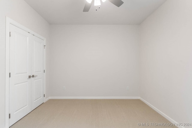 unfurnished bedroom featuring ceiling fan, a closet, and light carpet