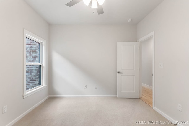 unfurnished room featuring ceiling fan, a wealth of natural light, and light carpet