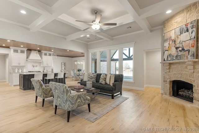 living room with coffered ceiling, ceiling fan with notable chandelier, beam ceiling, light hardwood / wood-style floors, and a fireplace