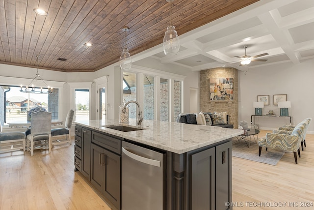 kitchen featuring sink, light wood-type flooring, stainless steel dishwasher, and decorative light fixtures