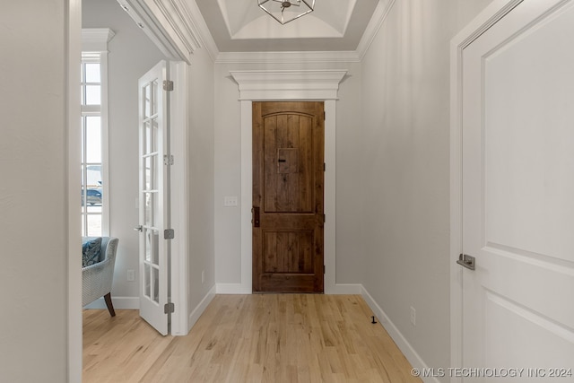 foyer entrance with crown molding, light hardwood / wood-style floors, and a tray ceiling