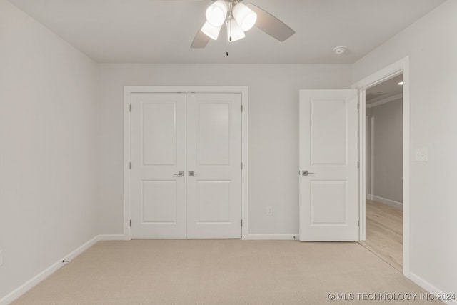 unfurnished bedroom with ceiling fan, light carpet, and a closet