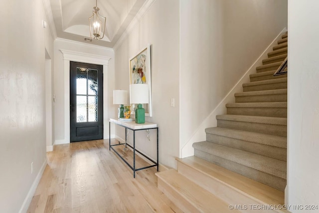 entryway with stairs, crown molding, a chandelier, light wood-type flooring, and baseboards