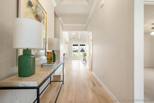 hall with crown molding, light wood-style floors, and baseboards