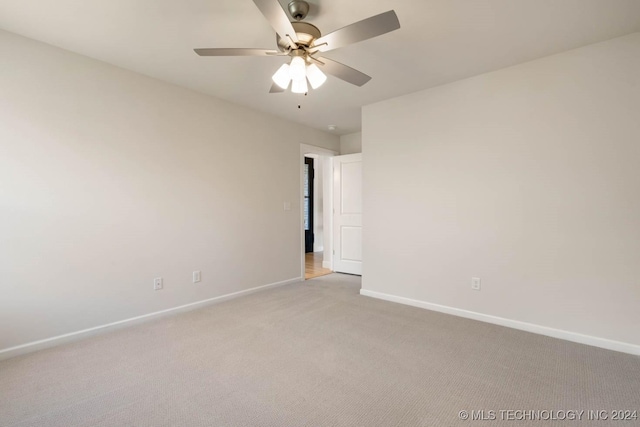 spare room with light colored carpet, baseboards, and a ceiling fan
