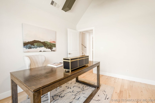 office with high vaulted ceiling and light hardwood / wood-style floors