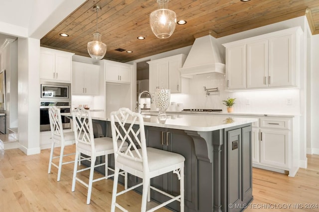 kitchen featuring stainless steel appliances, wood ceiling, white cabinets, light wood finished floors, and light countertops