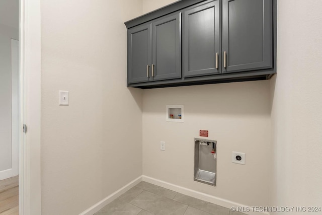 laundry area with cabinet space, hookup for an electric dryer, hookup for a washing machine, baseboards, and light tile patterned flooring