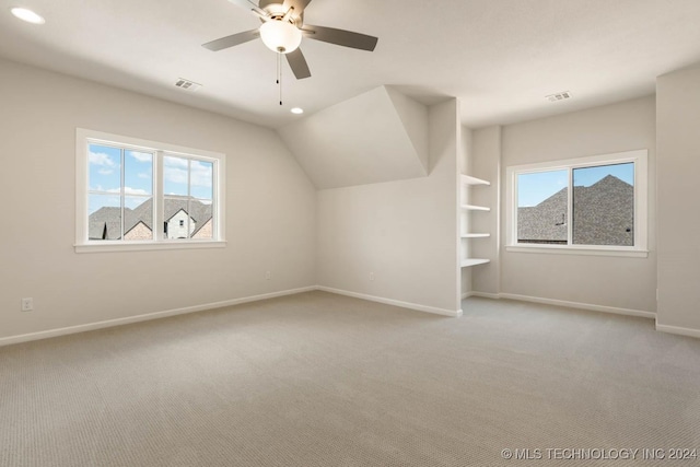 bonus room featuring carpet, baseboards, ceiling fan, built in shelves, and vaulted ceiling
