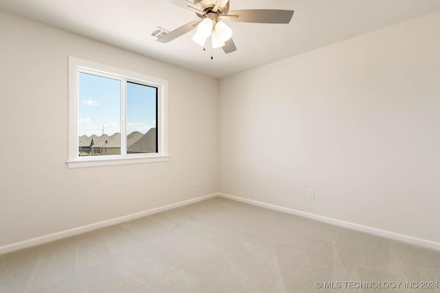 empty room featuring light colored carpet, baseboards, and a ceiling fan