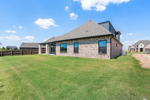 back of house with cooling unit, brick siding, and a shingled roof