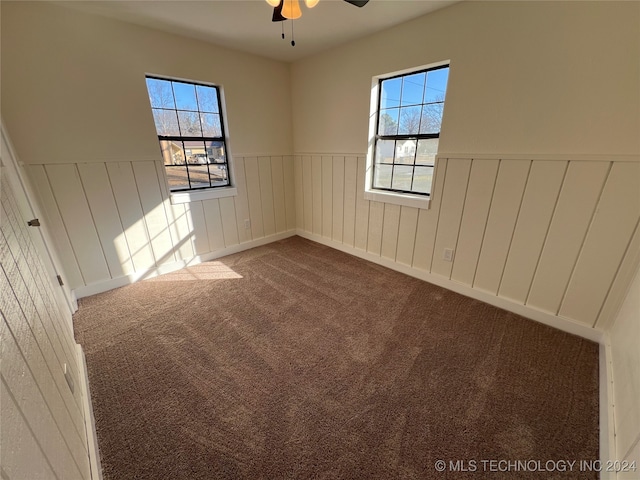 unfurnished room featuring plenty of natural light, ceiling fan, and carpet