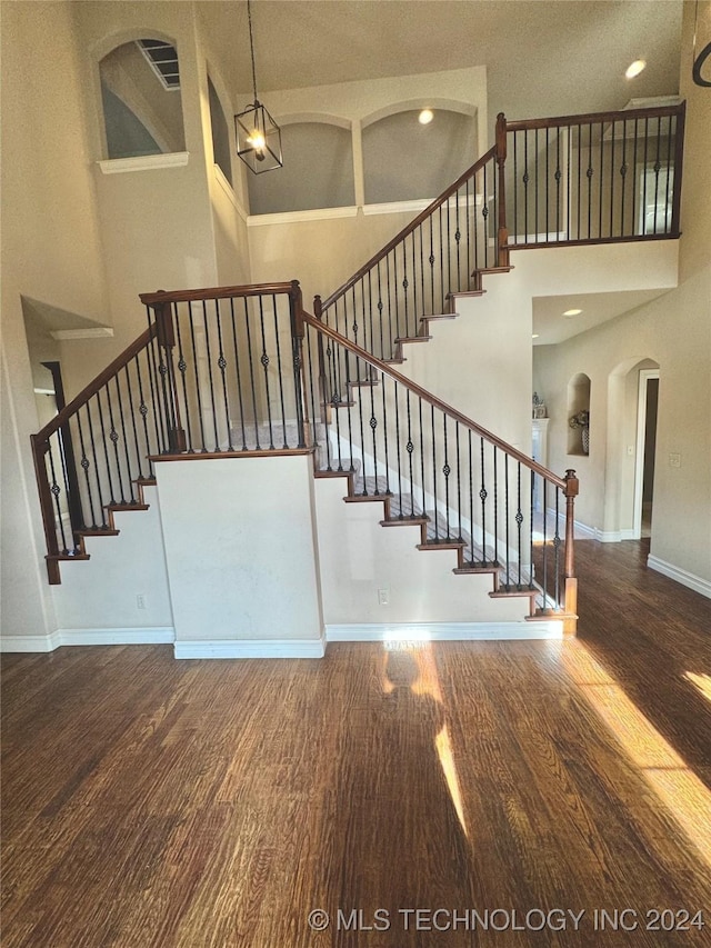 stairway featuring hardwood / wood-style flooring, a textured ceiling, and a high ceiling