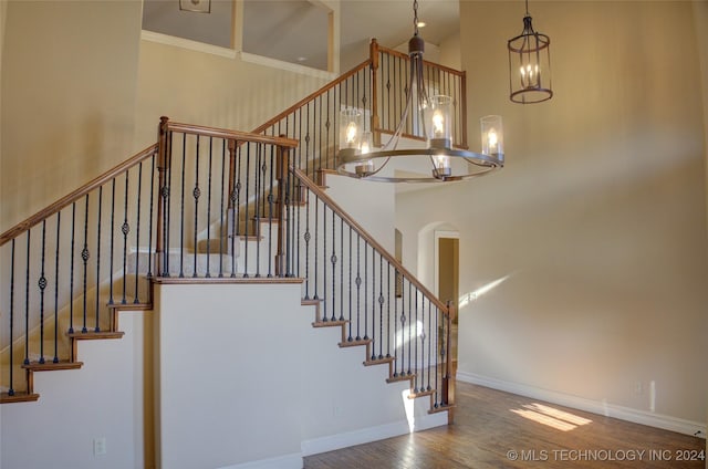 staircase featuring a high ceiling, an inviting chandelier, and wood-type flooring